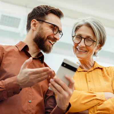 Two adults discuss information on a mobile device.
